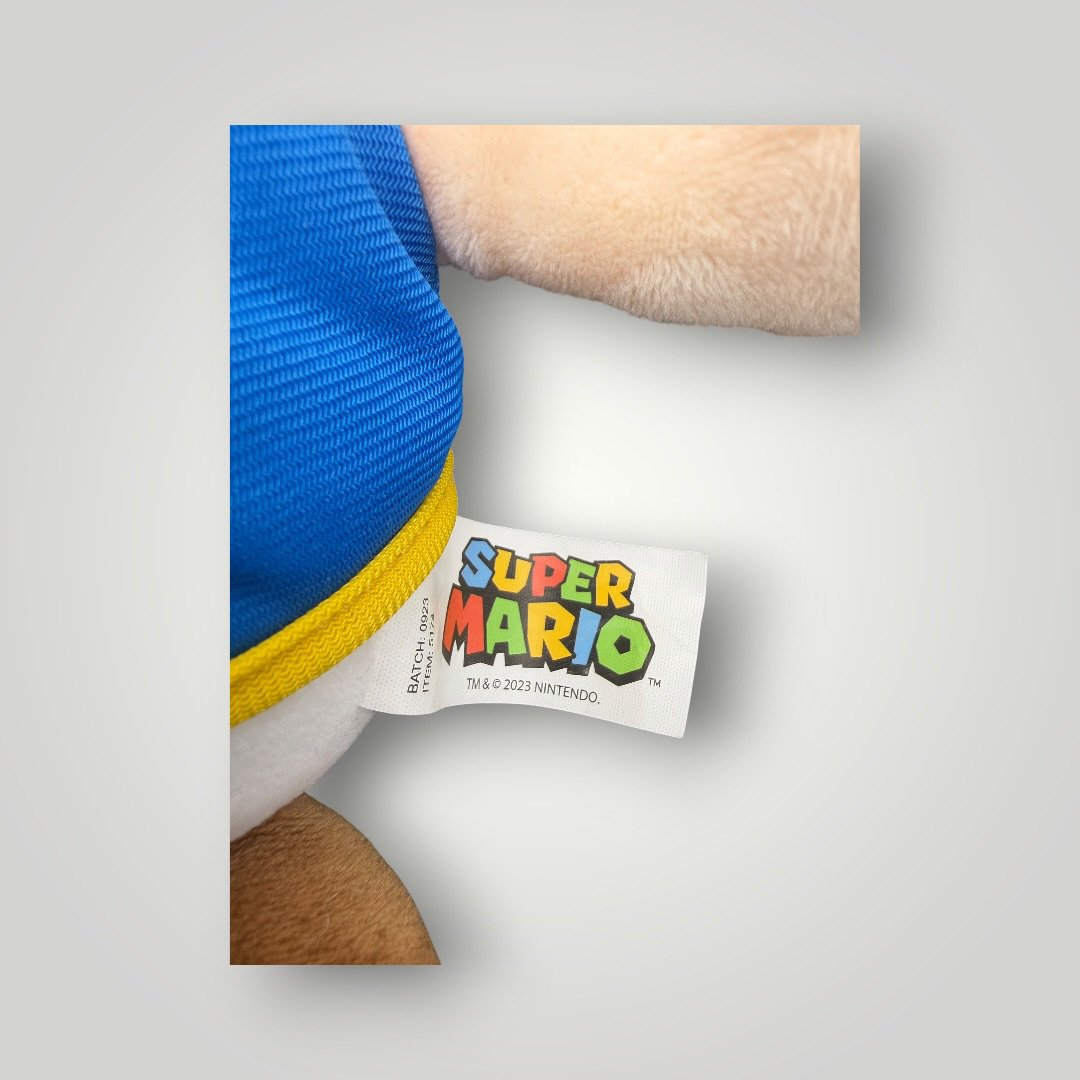 Die Bunte Box Gebrauchtwaren Super Mario Toad Plüschfigur mit blau-gelber Weste und rotem Pilzhut, weiches Stofftier.