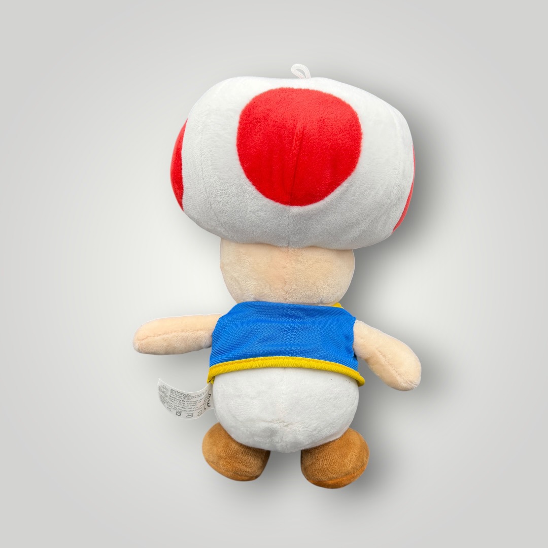 Die Bunte Box Gebrauchtwaren Super Mario Toad Plüschfigur mit rotem Pilzhut und blauer Weste, weiches Stofftier.