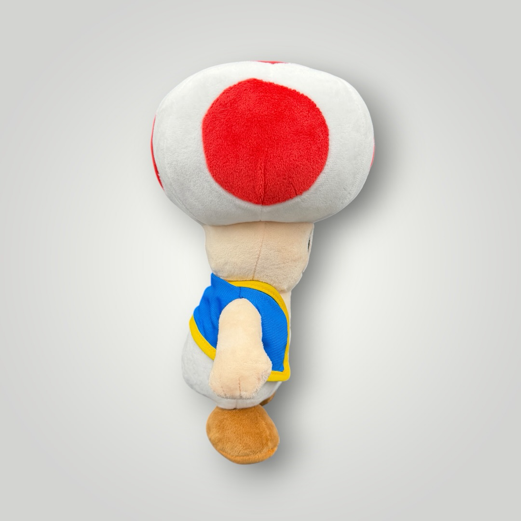 Die Bunte Box Gebrauchtwaren Super Mario Toad Plüschfigur mit rotem und weißem Pilzhut und blauer Weste.