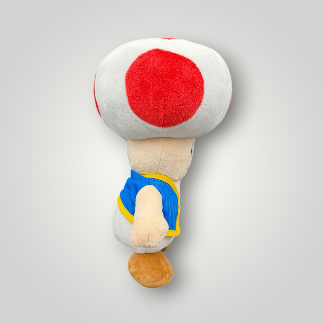 Die Bunte Box Gebrauchtwaren Super Mario Toad Plüschfigur mit rotem und weißem Pilzhut und blauer Weste.